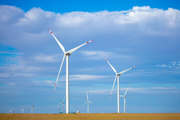 Fleet of power generators in motion. The blades of the wind farm rotate against the sky. The concept of extracting electricity from renewable sources. Wind turbine to generate electricity.