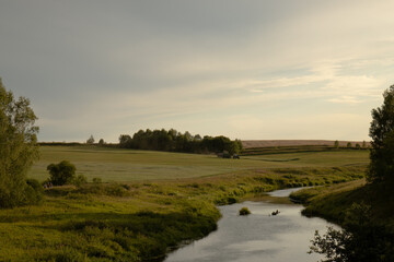 Obraz premium Harvesting. The combine harvester is in operation. The combine harvester harvests on the field. A wide field, a river and a combine harvester collects grain.