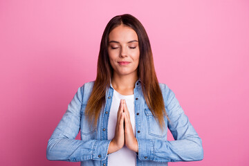 Fototapeta premium Beautiful young asian woman sitting in yoga position and meditating isolated over pink background