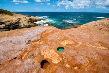 Turquoise blue hole in red sandstone cliff in Dominica