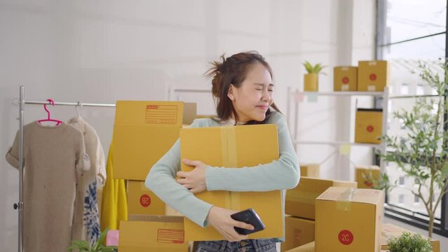 Asian female SME retail store owner is using her mobile phone to receive purchase orders expresses happiness at exceeding sales target