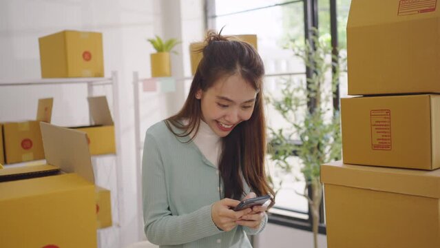 Asian female SME retail store owner is using her mobile phone to receive purchase orders expresses happiness at exceeding sales target