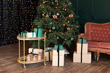Decorative golden trolley table with gifts and decor. Decorated Xmas tree with lights glowing garlands. Stylish loft living room interior with pink sofa. Christmas at home. New year winter home decor.