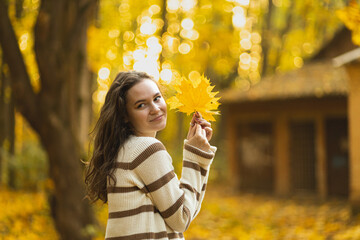 The girl holds a glass of coffee in her hands and enjoys the beautiful autumn weather.
