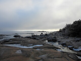 Obraz premium Scenic beach featuring a rocky shoreline with large chunks of melting ice against a clouded sky