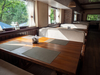 Interior of restaurant with wooden tables, chairs and tablecloth