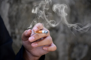 Closeup hand holding lighted cigarrette smoking of asian boys who starting to smoke in private area...