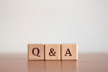 Questions and answers Q&A text on a background of wooden blocks placed on a blurred background table. Business and communication concepts - obrazy, fototapety, plakaty