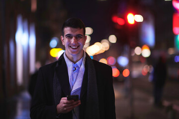 Smiling Meedle Eastern man walking down street near modern office building,