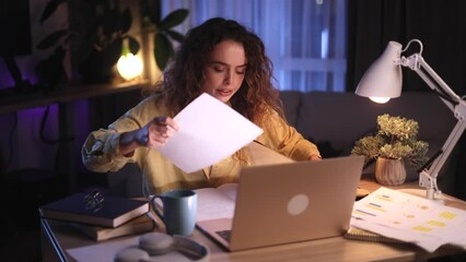 Worried young curly woman checking mail open envelope and celebrate win success reading great news feel amazed happy reading exam result enrolment letter at night at home Triumph Wow concept
