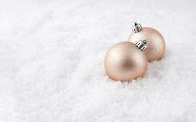 New Year balls of champagne color on snow. Seasonal banner. Selective focus, copy space