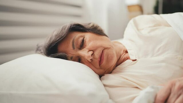 Senior woman lying on orthopedic pillow in the morning, healthy sleep cycle
