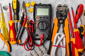 Electrician equipment on marble background with copy space.Top view.Electrician tool set.Multimeter, tester,screwdrivers,cutters,duct tape,lamps,tape measure and wires.Flet lay.