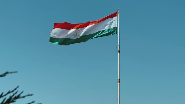 The national flag of Tajikistan on the flagpole in Penjikent. Asia. Video with the flag of Tajikistan waving, flag on a pole, horizontal, rectangular, raising the flag. 4K
