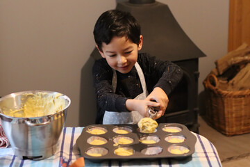 Baking concept Child play messy fancy cup cake muffin. Boy hand holding scoop putting cake batter...