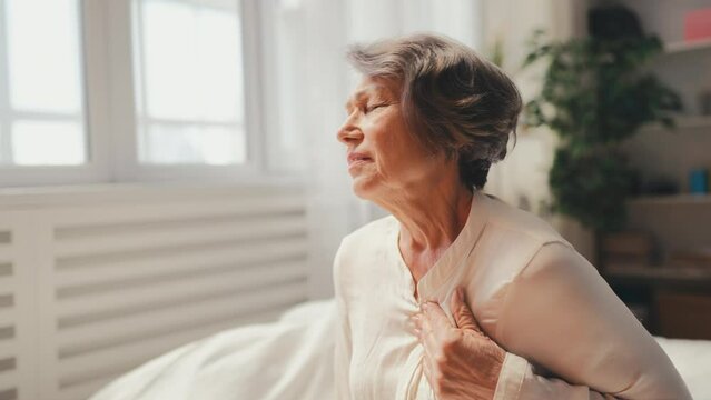 Unhappy senior woman suddenly feeling strong chest pain, risk of heart failure