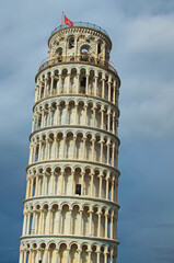 Detailed view of ancient Leaning Tower of Pisa against stormy sky and gloomy clouds. Notable landmark of Pisa, Italy. Travel and tourism concept. UNESCO World Heritage Site