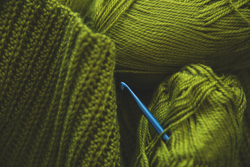 Skeins of demi-season light green yarn and a metallic blue hook. Crocheting, crochet design...