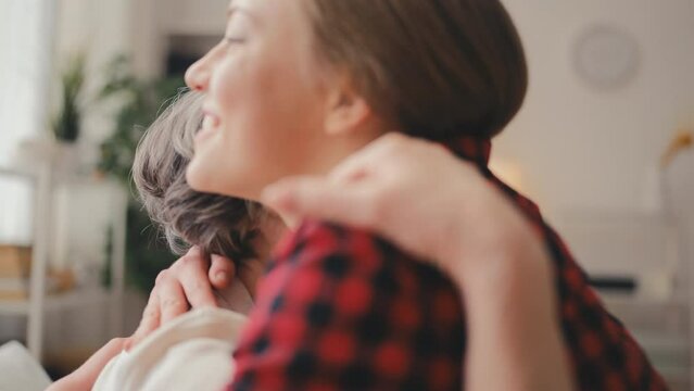 Young woman visiting grandmother at care home, hugging and supporting her