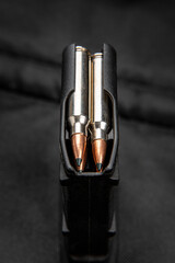 Close-up of .223 carbine cartridges. Loaded weapon clip. Weapons in the back