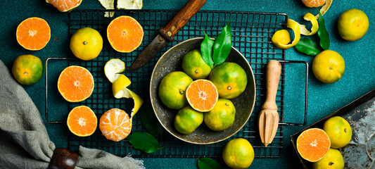Orange fruit with green leaves on the dark blue background. Home gardening. Mandarine oranges. Tangerine oranges. Orange color.