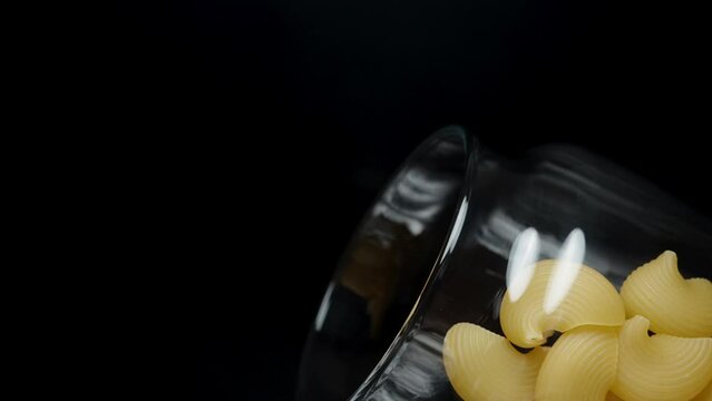Cooking pasta, macaroni shells fall from a can, slow-motion macro.
