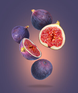 Whole and sliced ripe figs close up in the air on a purple background