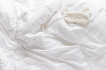 Sleeping mask from light fur on pillow on bed white bedclothes. Still life details, cozy life style...