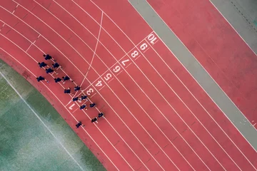 Zelfklevend Fotobehang Aerial view of a running track with a group of runners. © Wirestock
