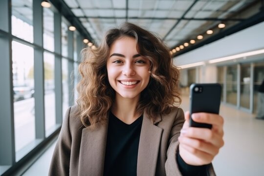 happy woman takes a selfie on a smartphone against the background of a house