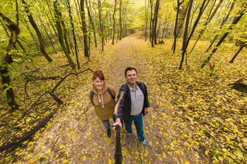 Couple against the backdrop of an autumn landscape. They film themselves using a selfie stick