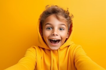 happy child boy takes a selfie on a smartphone against the background of a yellow