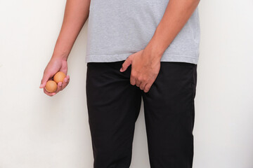 A man holding two eggs with his right hand and other hand holding crotch