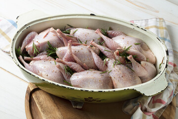 Raw quails stuffed with garlic and rosemary in a cast-iron saucepan before baking in the oven