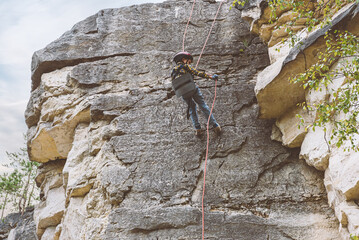 Small kid at rock climbing training learning basics of abseiling 