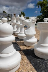 a chess board made from white plastic chess pieces sitting on a concrete floor