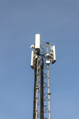 Fototapeta premium Communication tower isolated against the background of a blue sky.