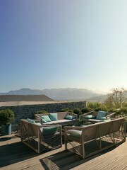 Fototapeta premium Cozy outdoor patio setup with a wooden table and chairs set against a classic stone wall