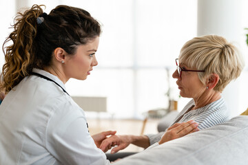Obraz premium Kind attentive healthcare nurse discussing treatment plan with senior woman at nursing home