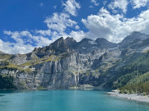 Landscape of a crystal-clear lake surrounded by rocky mountains in Switzerland