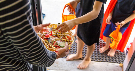 Children take candy from a basket. Halloween.