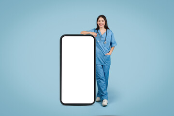 Smiling female nurse near huge phone with blank screen
