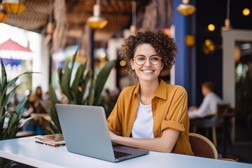 happy woman sitting at table with laptop in cafe - Powered by Adobe