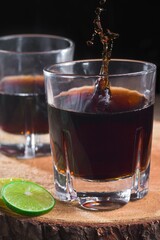 Vertical shot of two glasses of alcoholic drinks with soda and lime on the table