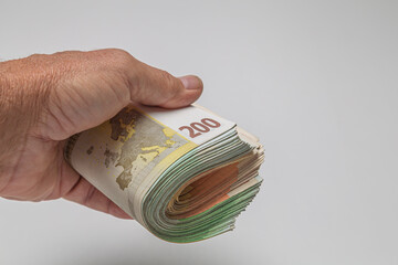 Hand holding a stack of euro banknotes on a white background
