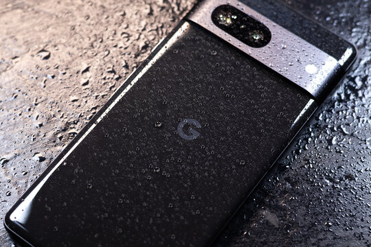 KYIV, UKRAINE - October 03, 2023 :  Modern smartphone Google Pixel with water drops on black background. Water resistant modern technology.