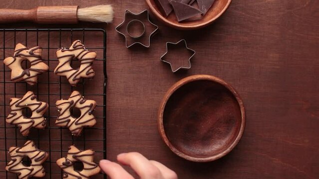 A human's hand places a homemade star-shaped cookie with chocolate in a wooden plate