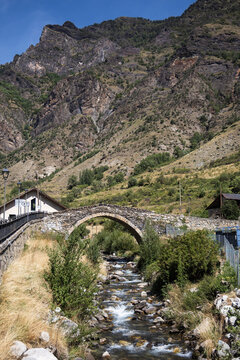 Medieval stone bridge over the river in Espot village in Pyrenees mountains, summer