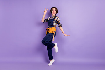 Fototapeta premium Full length body size photo of woman wearing overall showing v-sign gesture isolated on pastel purple color background