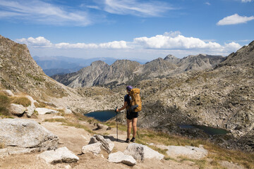Hiker in a beautiful landscape of the natural park of Aigestortes y Estany de Sant Maurici, Pyrenees valley with river and lake
